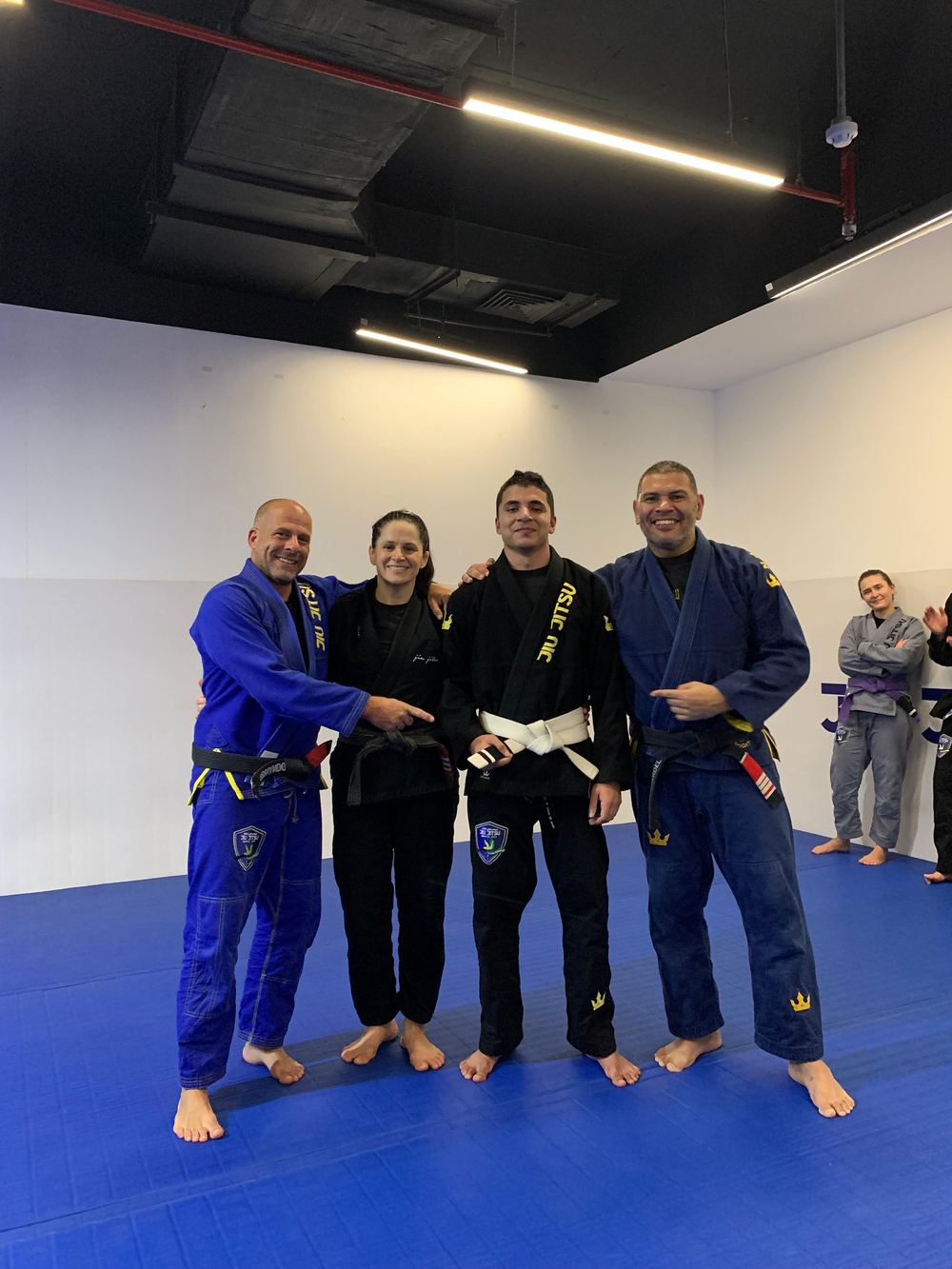 Adult students celebrating a belt promotion at JJMA Qatar